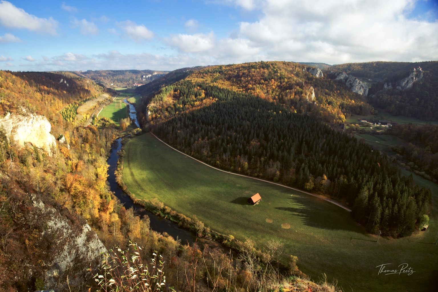 Weiter Blick vom Knopfmacherfelsen über die Donau, grüne Wiesen und herbstliche Waldhänge