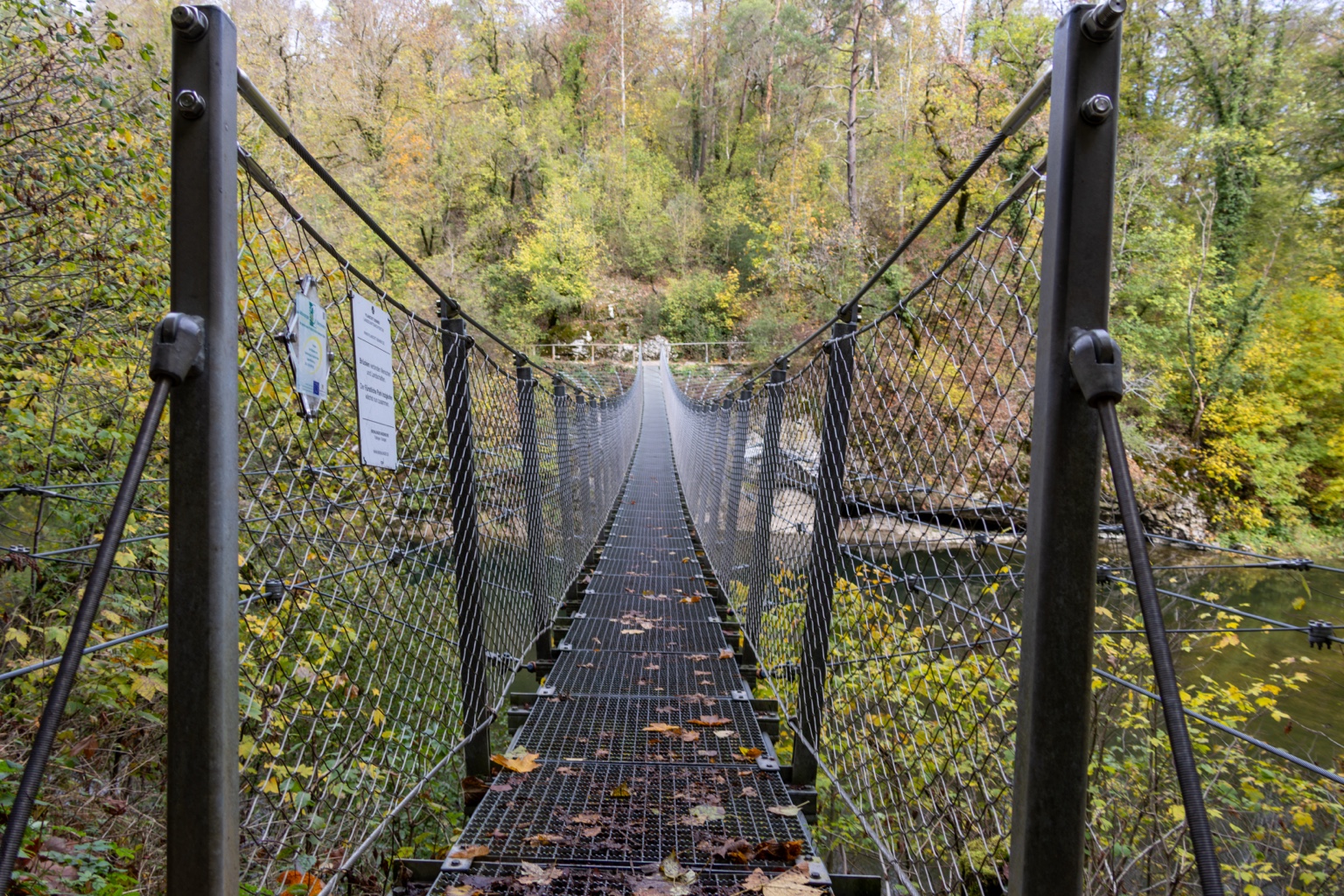 Blick längs über die Hängebrücke mit Drahtseilen und Gitterboden
