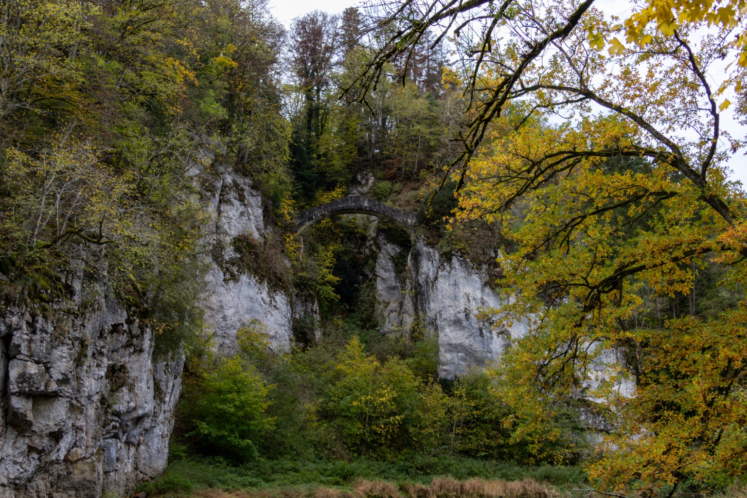 Blick auf die Teufelsbrücke zwischen Felswänden und gelbgrünen Bäumen