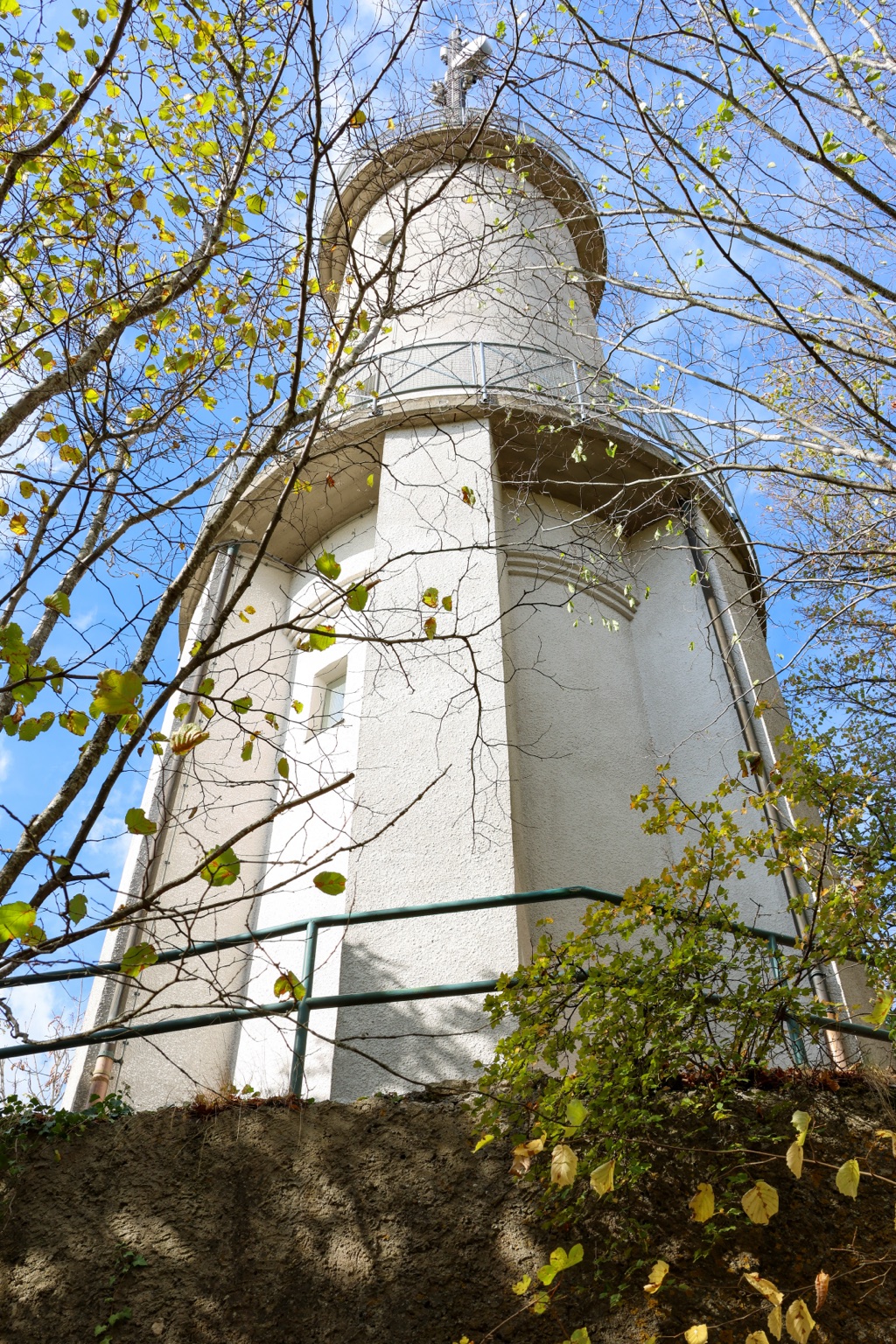 Schlossfelsenturm von unten zwischen Zweigen und gelbgrünen Blättern vor blauem Himmel